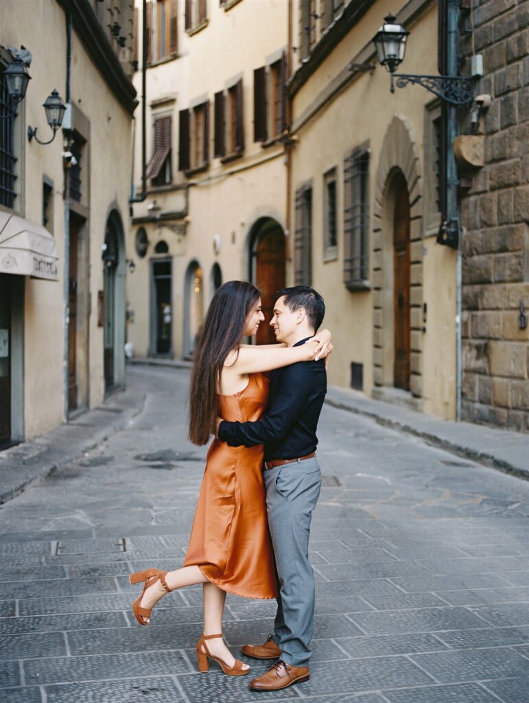 Couple wandering the beautiful cobblestoned streets of Florence Italy for their honeymoon, the beautiful sights of Ponte Vecchio, the Arno river, and more, image photographed by Kelley Williams a Florence Italy wedding photographer