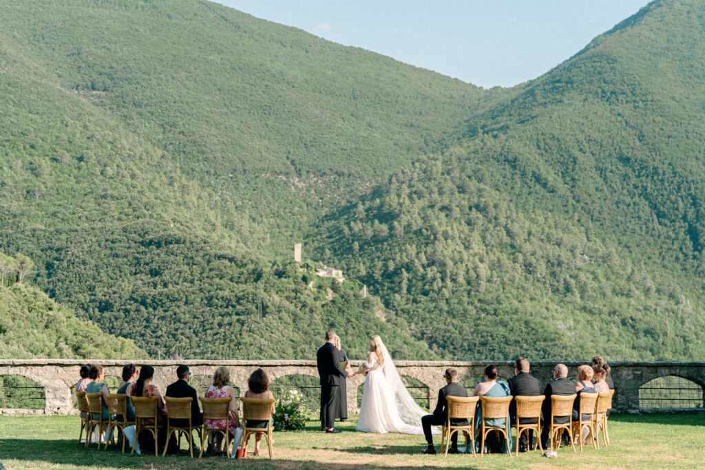 Wedding couple getting married in front of 15 people overlooking a green valley at Abbazia San Pietro in Valle, image taken by Kelley Williams a wedding photographer in Umbria Italy