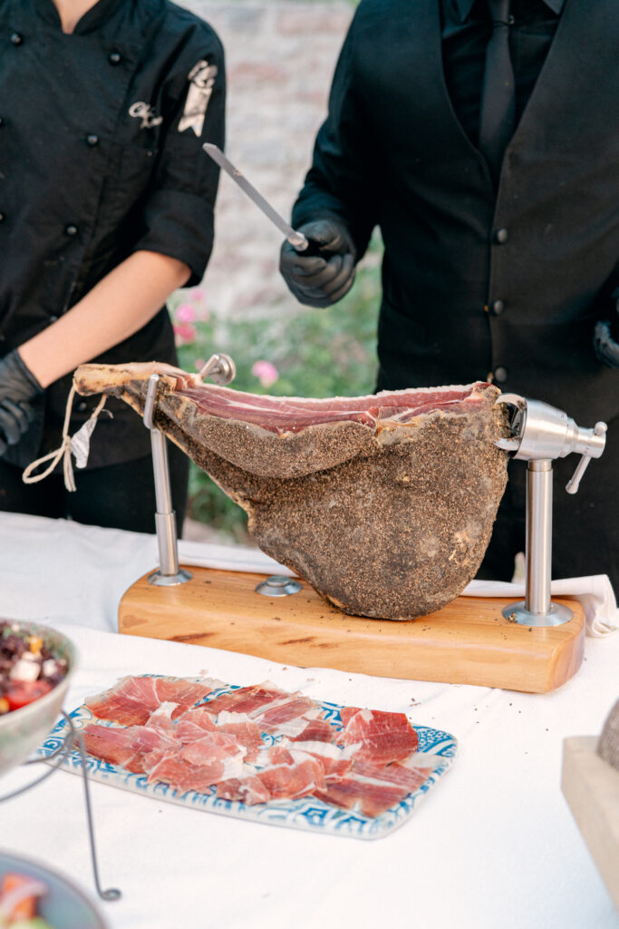 A closeup photo of fresh prosciutto being cut for guests during cocktail hour, Abbazia San Pietro in Valle wedding, image taken by Kelley Williams a wedding photographer in Umbria Italy
