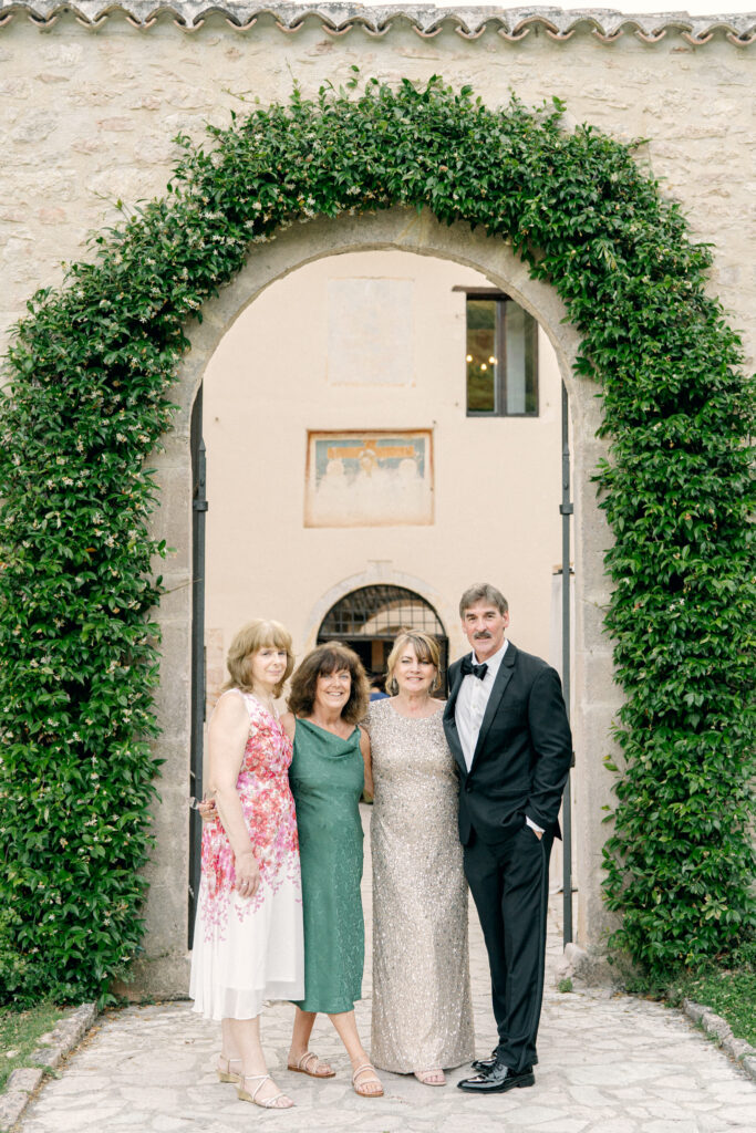Wedding guests in front of an archway covered in greenery, Abbazia San Pietro in Valle wedding, image taken by Kelley Williams a wedding photographer in Umbria Italy