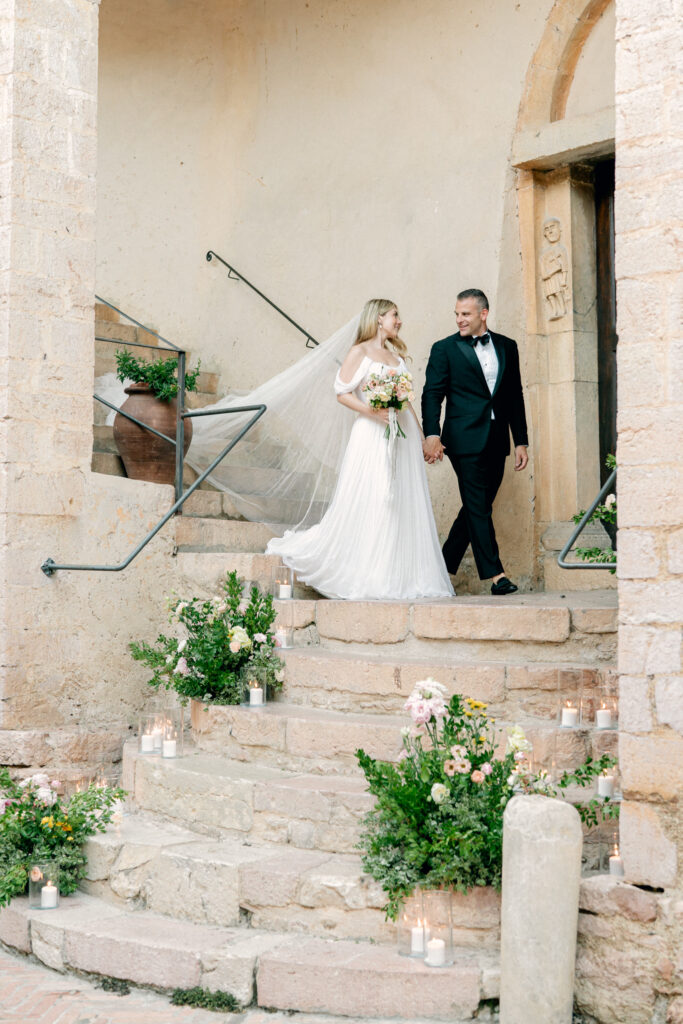 Bride and groom, reentering the wedding reception walking down the stairs, Abbazia San Pietro in Valle wedding, image taken by Kelley Williams a wedding photographer in Umbria Italy 