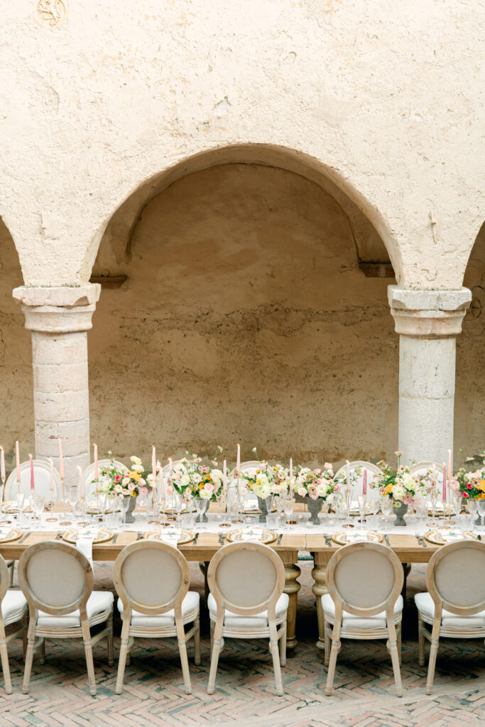 View of wedding reception table in front of large archways, Abbazia San Pietro in Valle wedding, image taken by Kelley Williams a wedding photographer in Umbria Italy