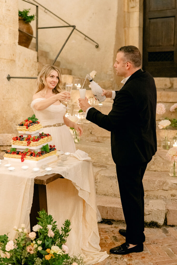 Couple pouring champagne after cutting the cake, Abbazia San Pietro in Valle wedding, image taken by Kelley Williams a wedding photographer in Umbria Italy